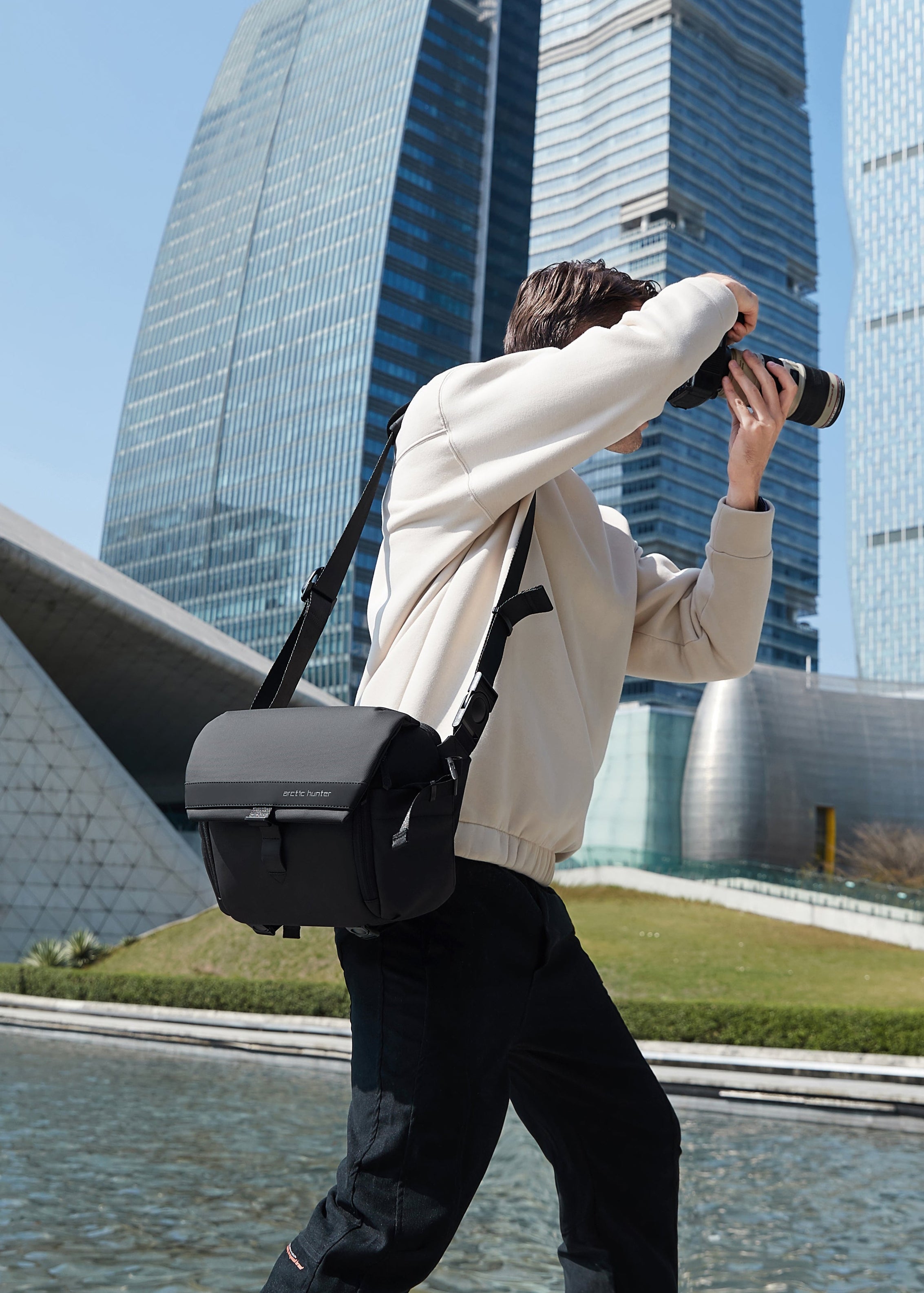 Fotograf mit ArcticFlex Pro Kameratasche fotografiert in moderner Stadtkulisse – zeigt hochwertige Verarbeitung und langlebige Qualität.