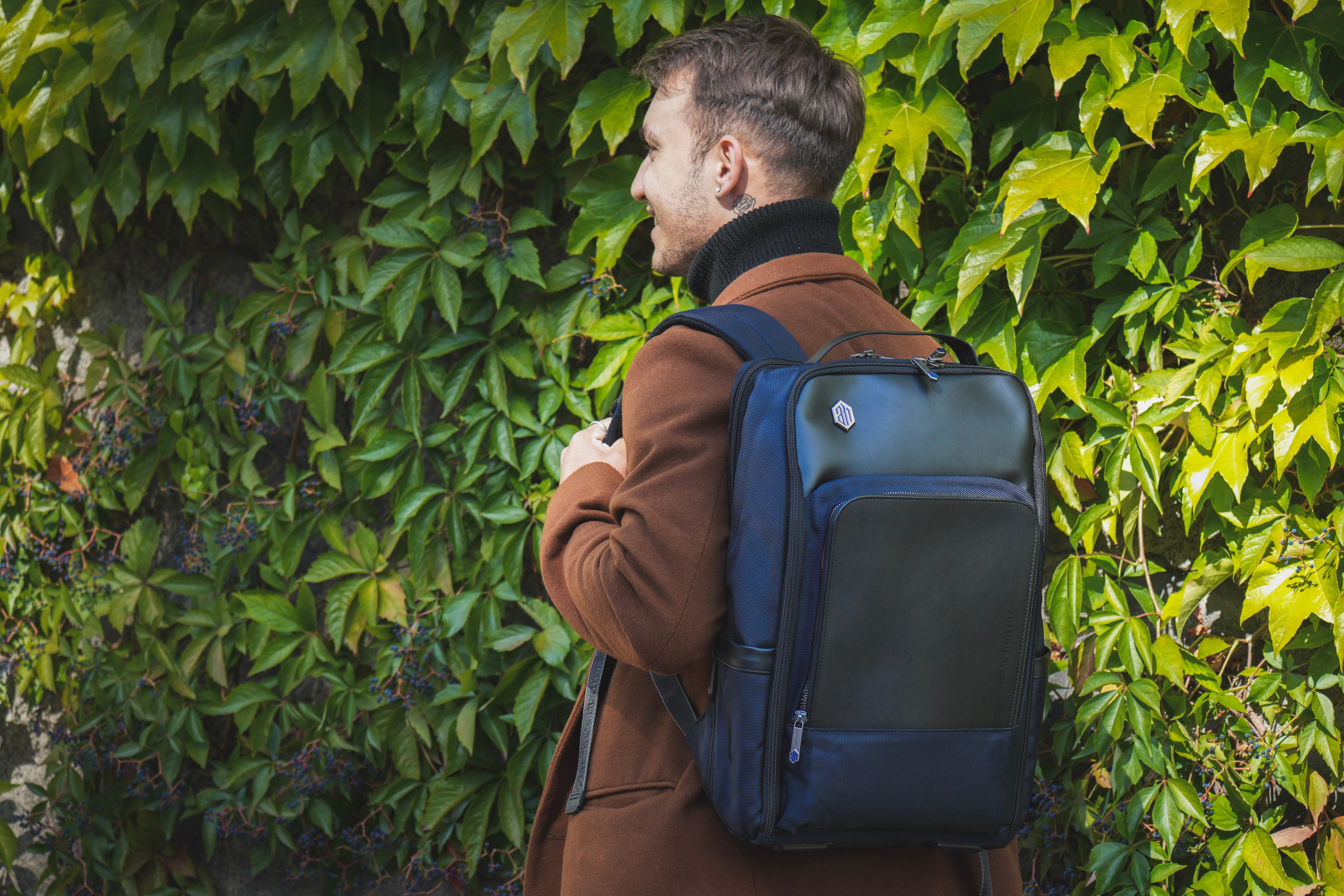 Mann mit wasserabweisendem Rucksack im Herbst-Outfit vor herbstlicher Stadtkulisse