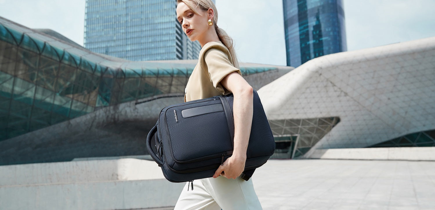 Frau in modernem Business-Outfit hält einen minimalistischen Rucksack in der Hand und geht dynamisch durch die Stadt.