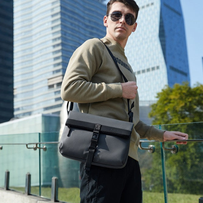 Mann trägt Arctic Hunter Crossbody Charm Tasche über der Schulter beim Reisen