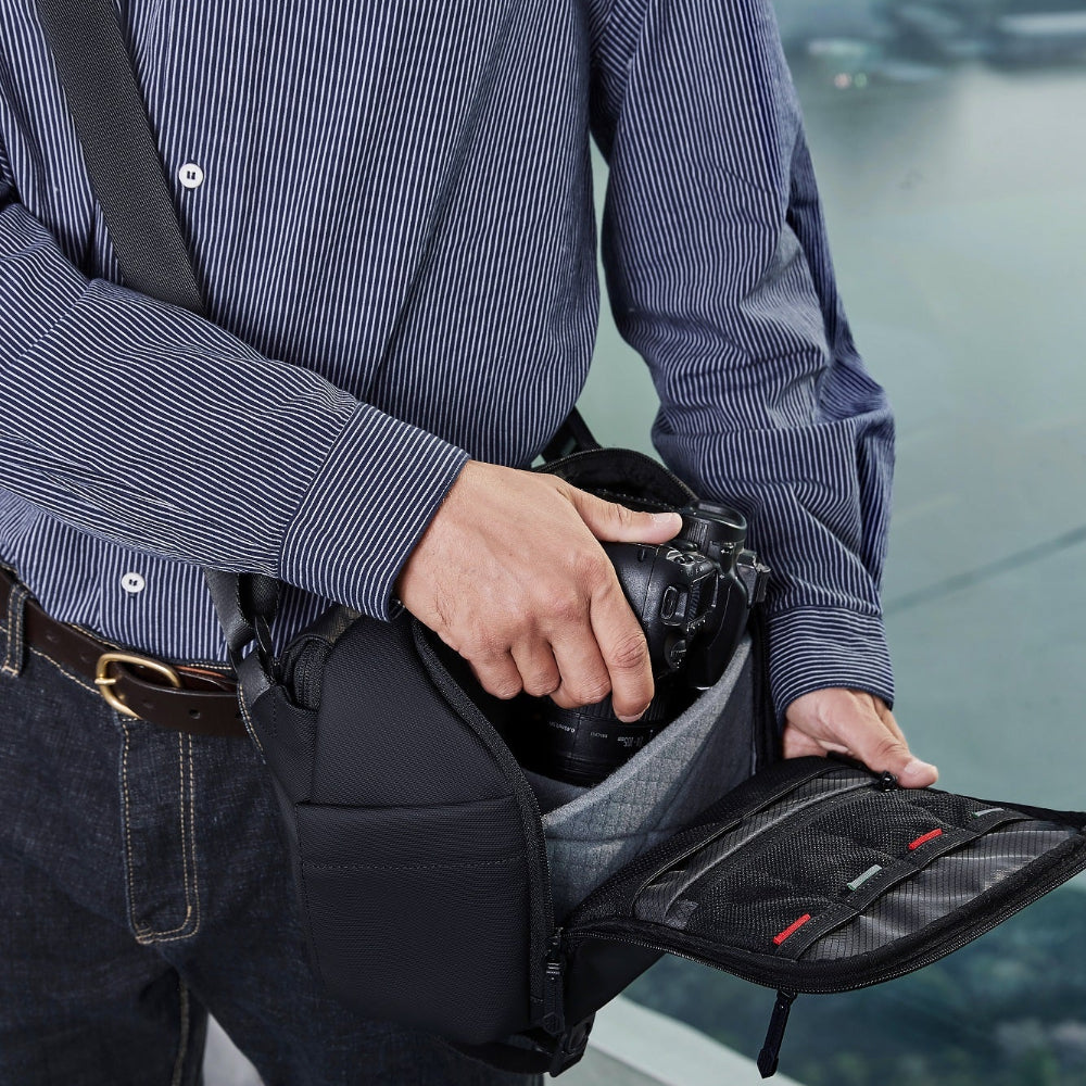 Ein Mann legt eine Kamera in eine hochwertige Unisex-Kameratasche von Arctic Hunter, erhältlich bei SC-Bag. Die Tasche wirkt robust, funktional und schützt das Equipment zuverlässig beim Transport.