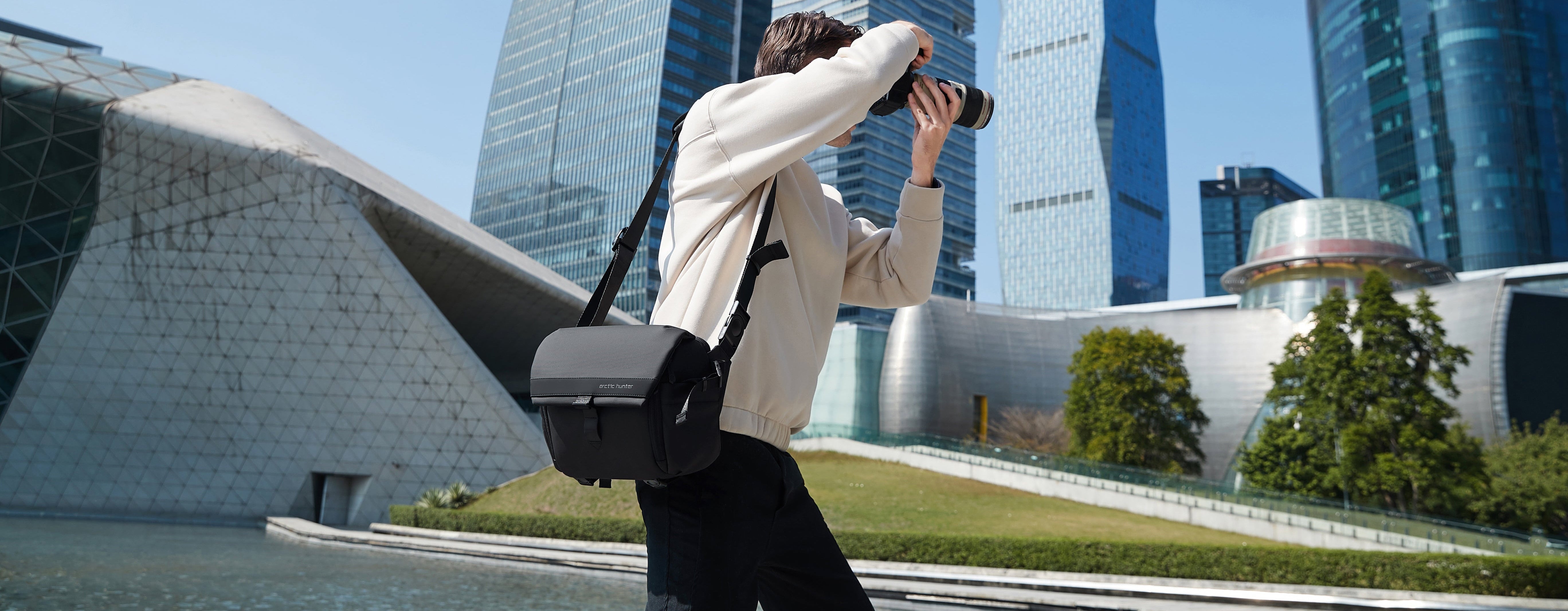 Fotograf mit ArcticFlex Pro Kameratasche fotografiert in moderner Stadtkulisse – zeigt hochwertige Verarbeitung und langlebige Qualität