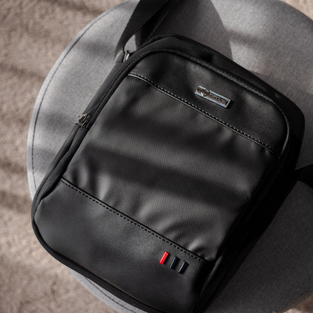 Seitenansicht von vorne auf die schwarze Reisefreund Schultertasche von arctic hunter, die das schlanke Profil und die kompakte Form der Tasche zeigt.