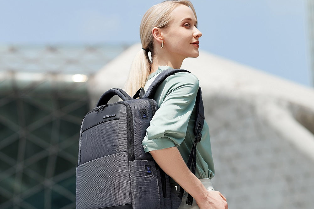 Eine Frau trägt den grauen ClassicTech Laptop-Rucksack in einer modernen Architektur-Umgebung – stilvoller Begleiter für Business und Alltag.