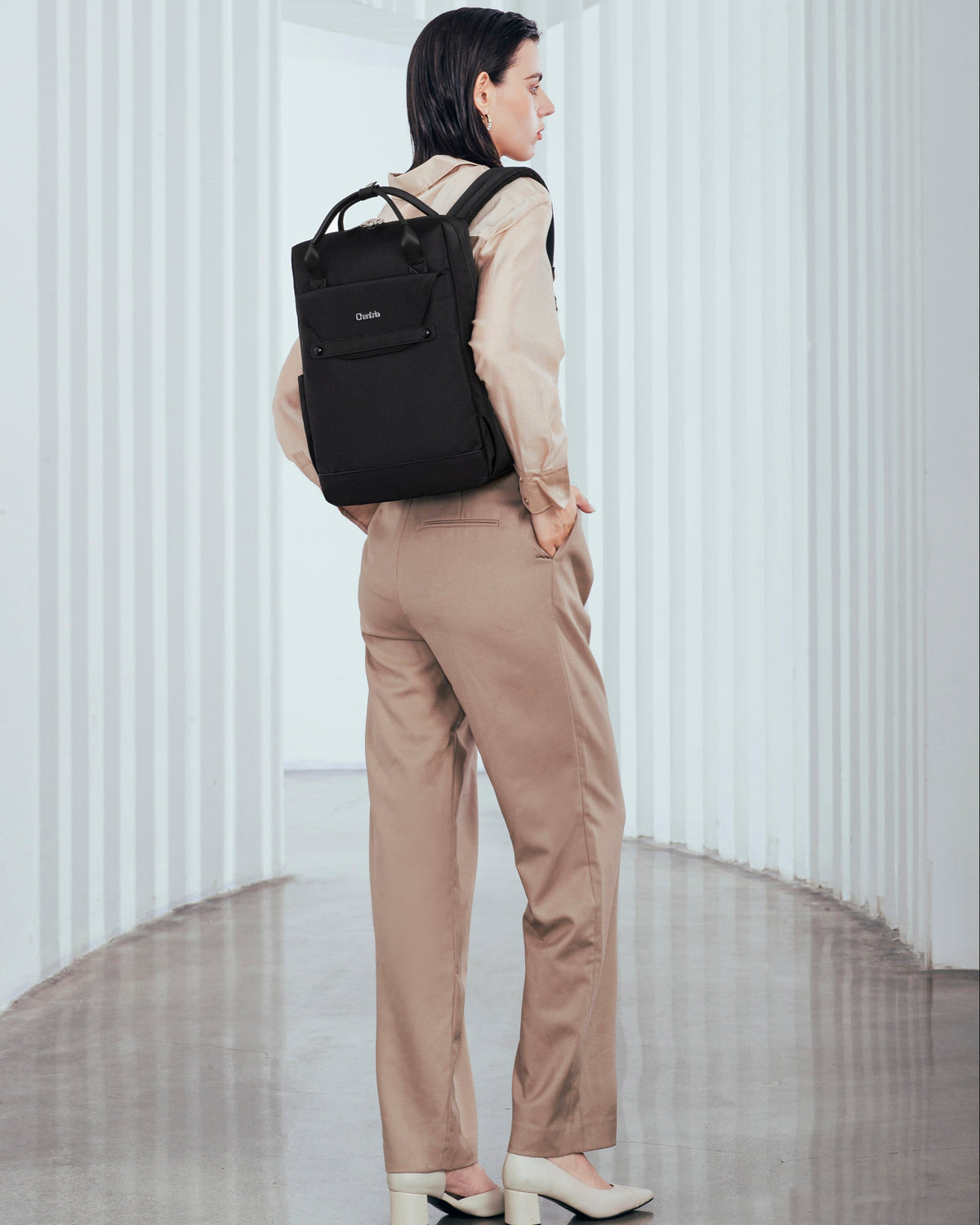 Dame im eleganten Outfit mit schwarzem Rucksack in einem modernen, hellen Innenraum