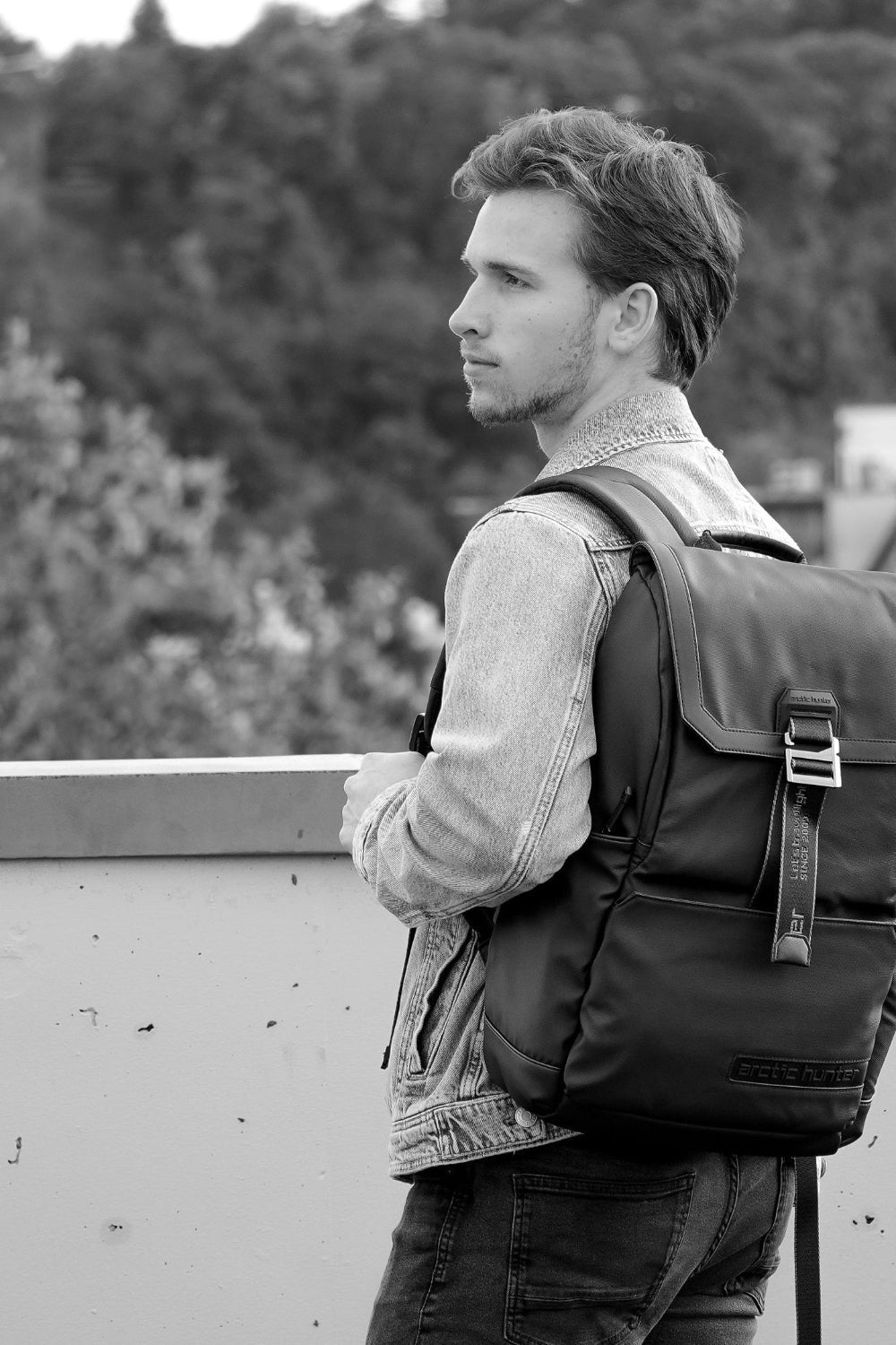 Mann trägt einen schwarzen Rucksack für Reisen und Alltag vor moderner Stadtkulisse.