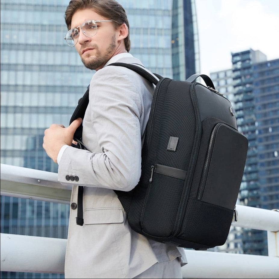Business Rucksack Herren – Mann in Anzug trägt stilvollen, schwarzen ergonomischen Rucksack für Arbeit und Reisen