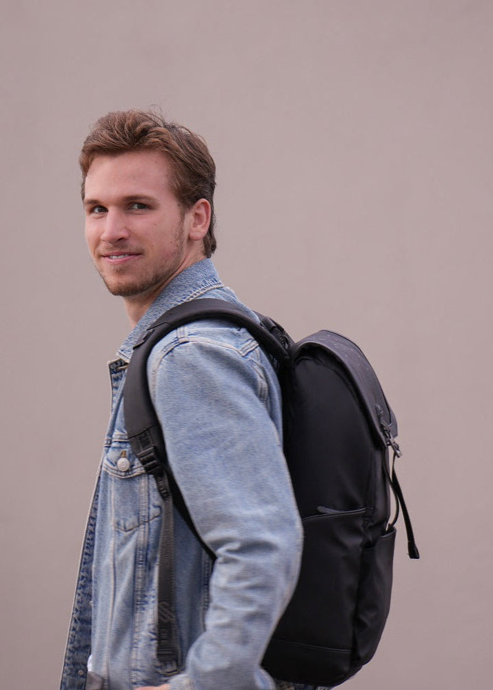 Mann trägt den Jet Black Rucksack im urbanen Style – modern, ergonomisch und vielseitig