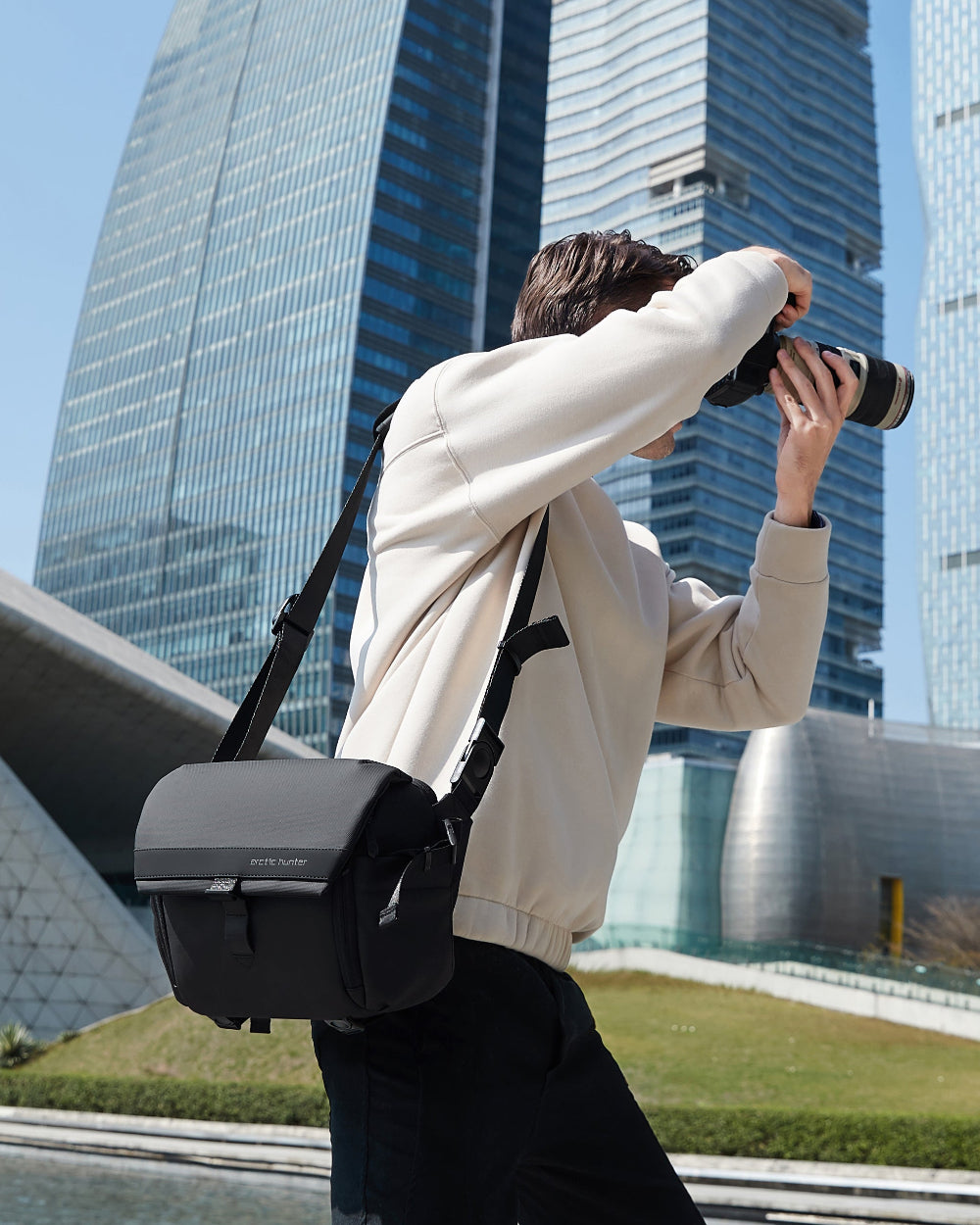 Fotograf mit schwarzer Kameratasche arcticflex-pro im urbanen Umfeld – wasserabweisende, hochwertige Kameratasche für Reisen und Alltag