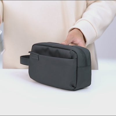 Video zeigt, wie Smartphone, Karten, Schlüssel und weitere Essentials in der Travel Pouch Lite verstaut werden und wie das Modell anschließend getragen präsentiert wird.