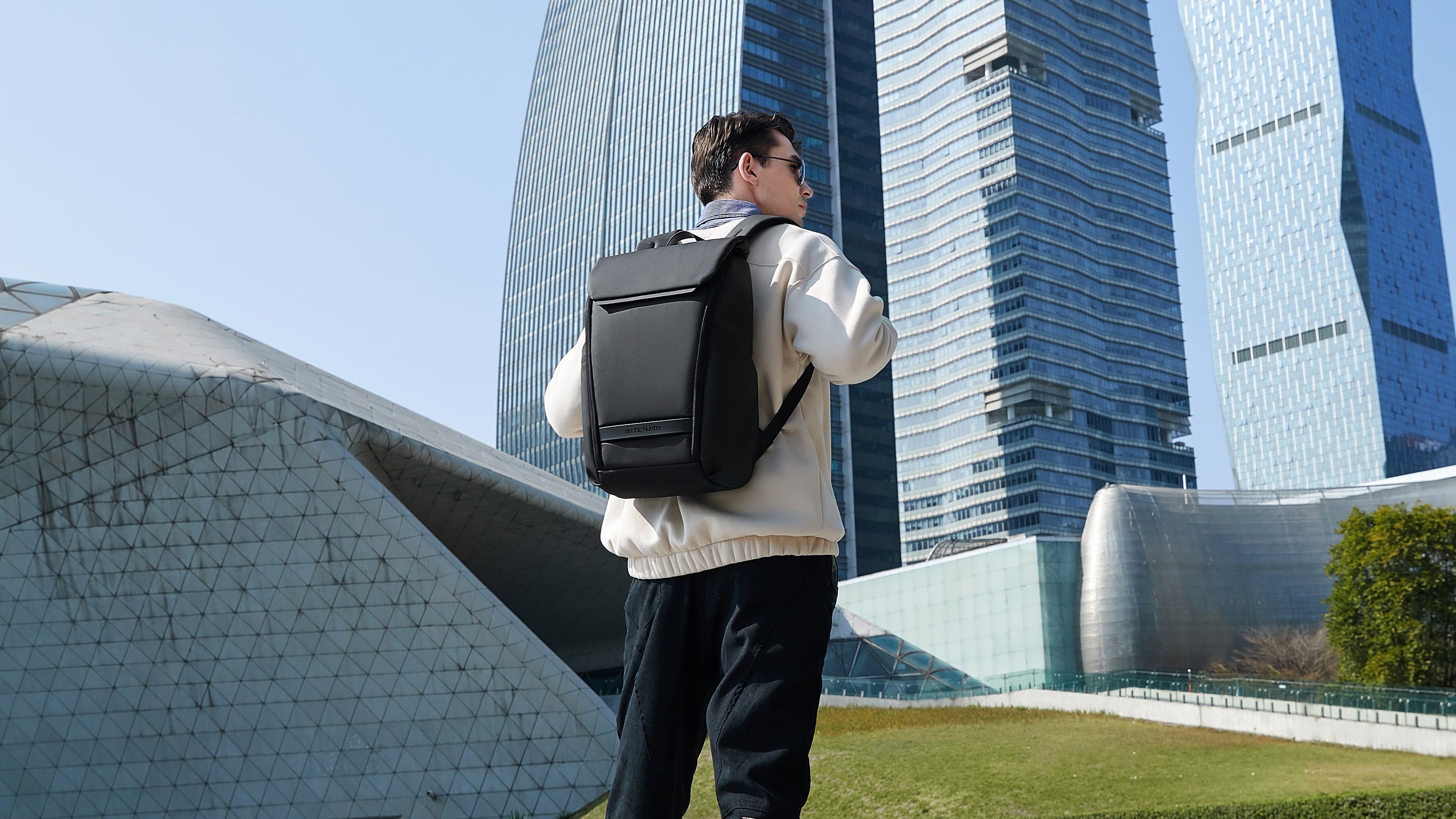 Ein Mann mit dem schwarzen SC Bag Flexipack Rucksack vor einer modernen Stadtkulisse – perfekt für Pendler und den urbanen Alltag
