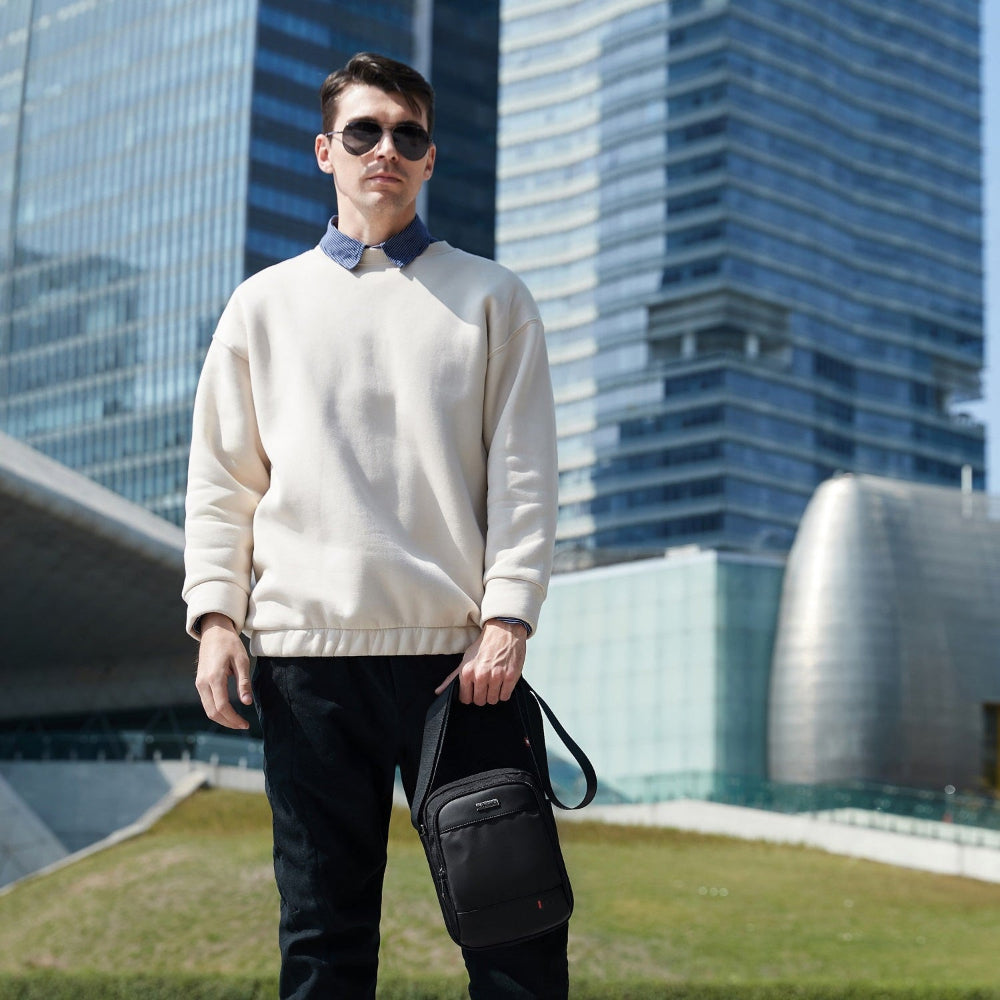 Mann mit Casual-Outfit trägt die Schultertasche „Reisefreund“  in urbaner Stadtkulisse – moderne Umhängetasche.